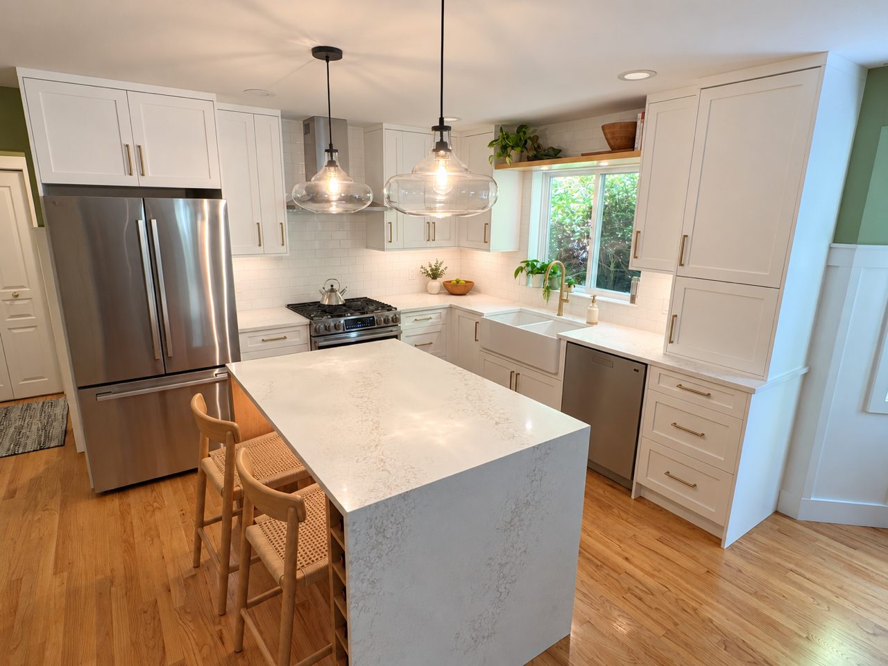 White shaker kitchen with a quartz waterfall island and glass pendant lights